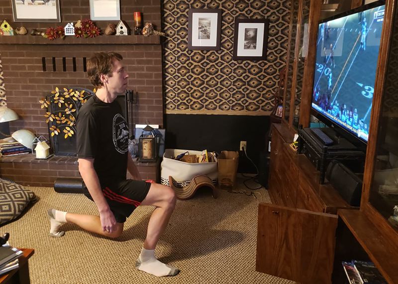 CONTRIBUTED PHOTO - Eastwind Running Club member Scott Pesznecker does some stretching while watching the replay of an historic Oregon Ducks football game. 