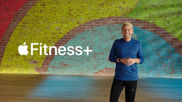 Apple Fitness+ leader standing in front of as rainbow wall