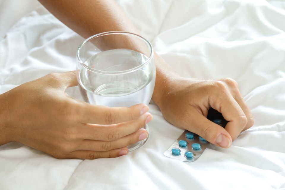 Female hands with a glass of water and blister pack with pills